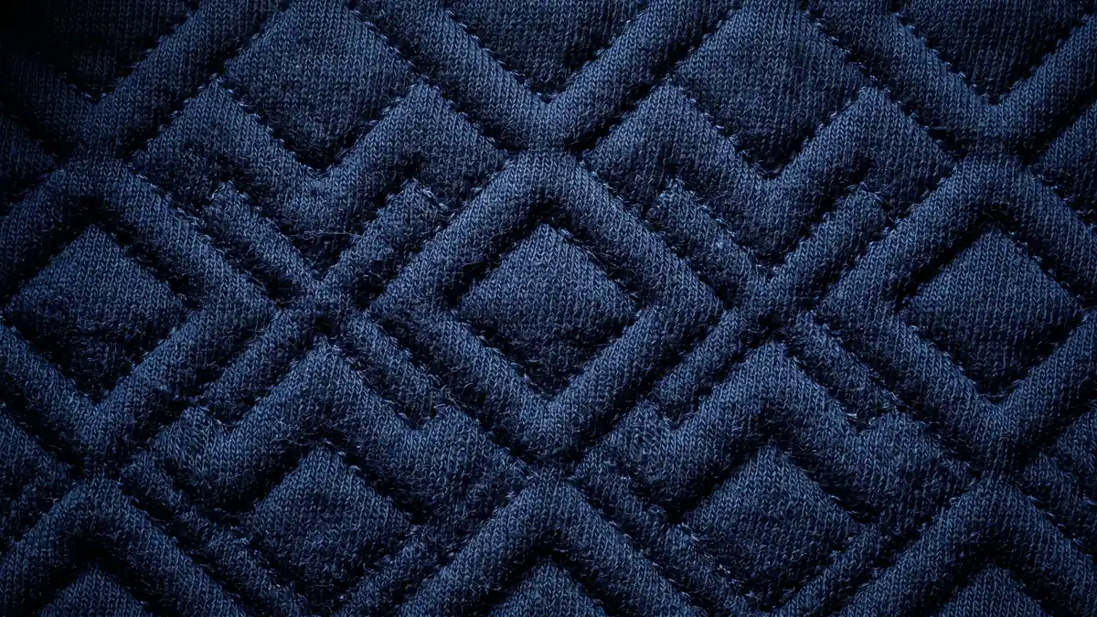 Tendenze tessili 2026: macro del matelasse tridimensionale blu notte costruito nell'intreccio